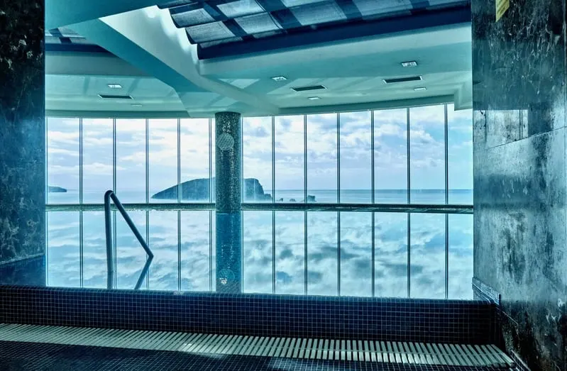 Indoor pool looking through glass to the sea