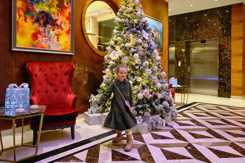 A child beside a Christmas tree in a hotel lobby