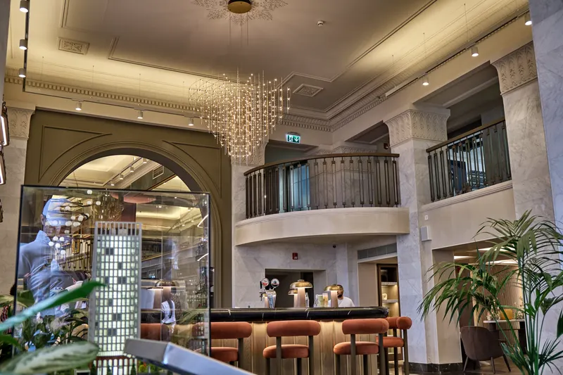 Hotel bar beneath a crystal chandelier and a marble balcony