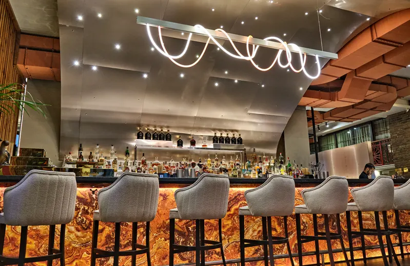 Bar with a glowing ribbon light and an amber stone front